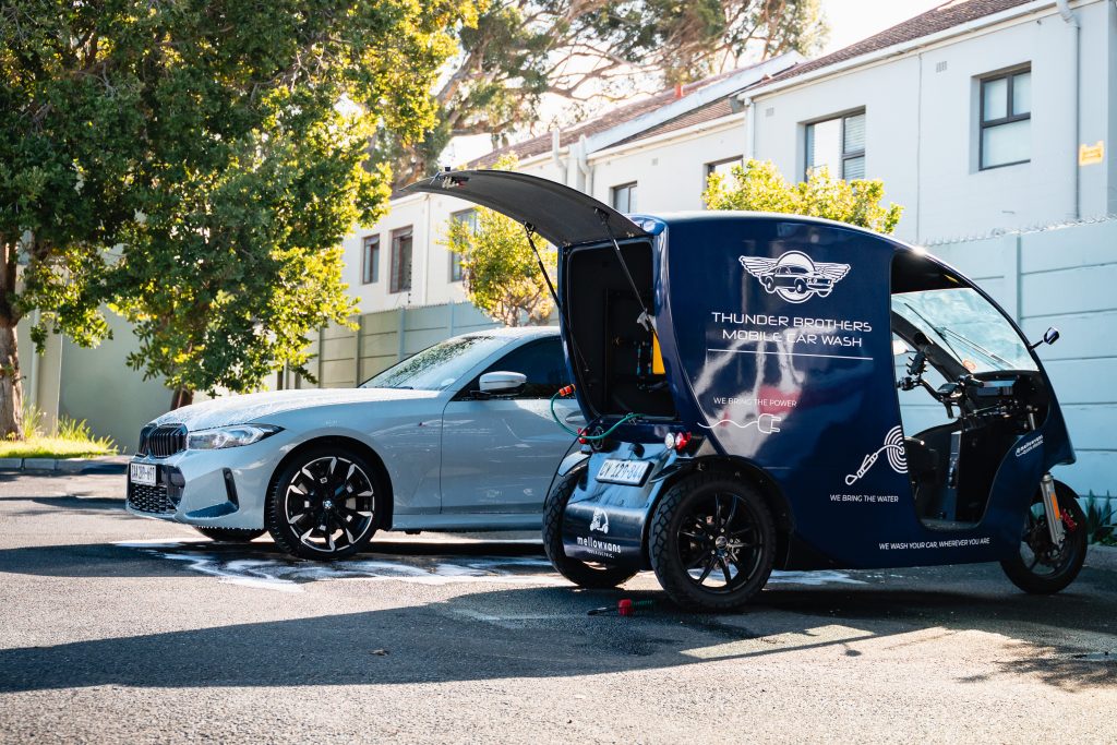 Thunder Brothers mobile car wash unit parked beside a car being washed outside a home