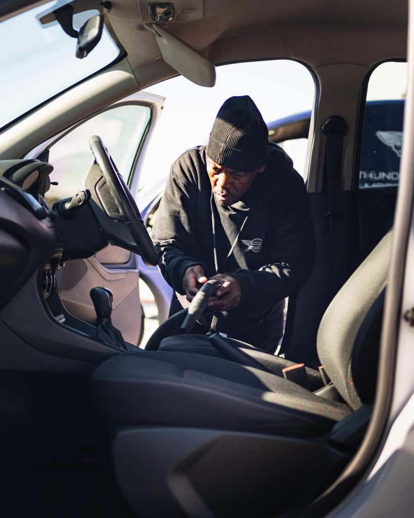 A Thunder Brothers technician vacuuming a car interior during a valet