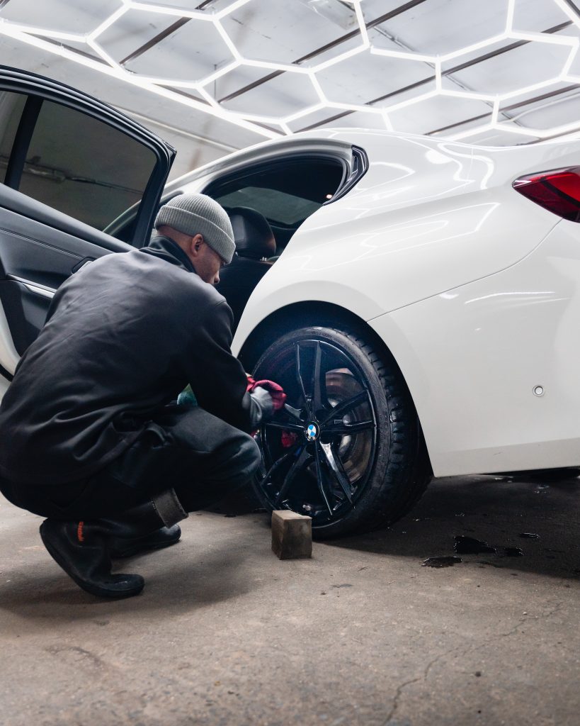 A Thunder Brothers technician detailing an alloy wheel by hand with a microfibre cloth