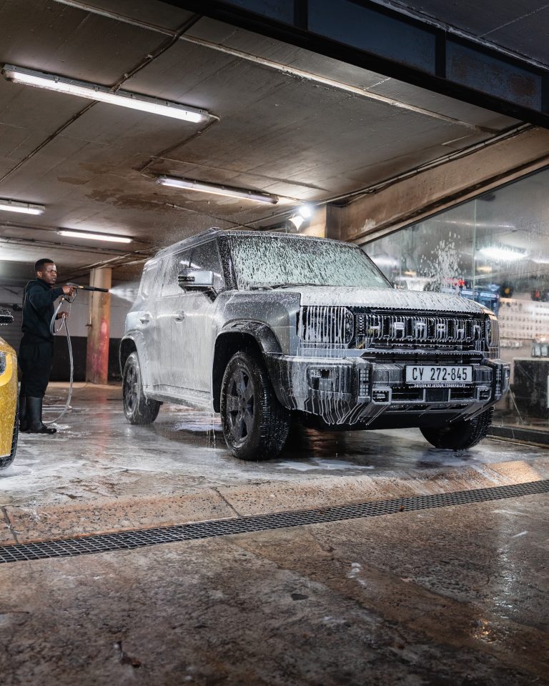 A Thunder Brothers technician pressure washing a foam covered SUV at a branch