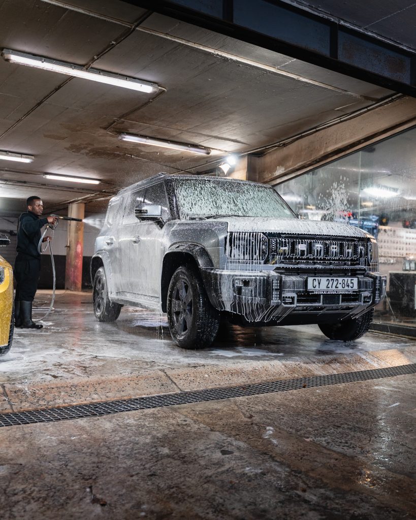 A Thunder Brothers technician pressure washing a foam covered SUV at a branch