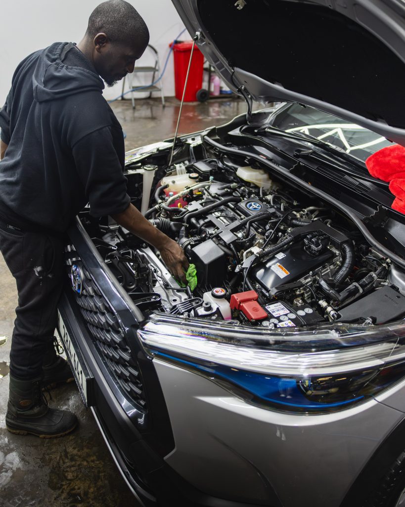 A Thunder Brothers technician cleaning an engine bay by hand
