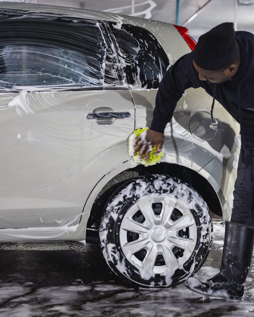 A Thunder Brothers technician hand washing a car with a wash mitt
